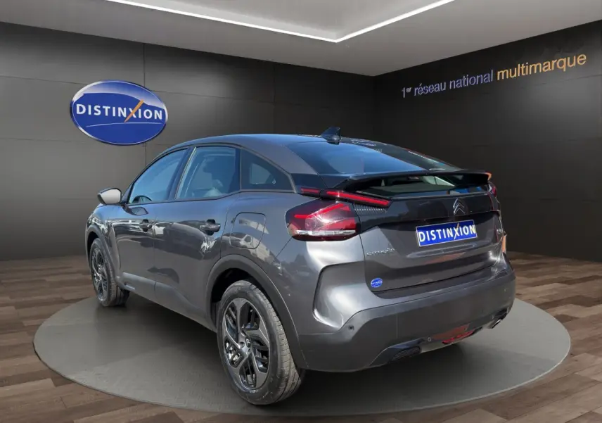 Vue 3/4 arrière droite d'une Citroën C4 gris foncé 2023 avec feux LED et jantes noires distinctives.