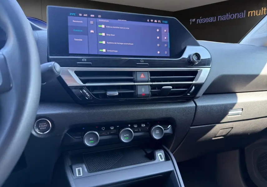 Vue intérieure du tableau de bord de la Citroën C4 2023, écran tactile central et commandes climatisation visibles.