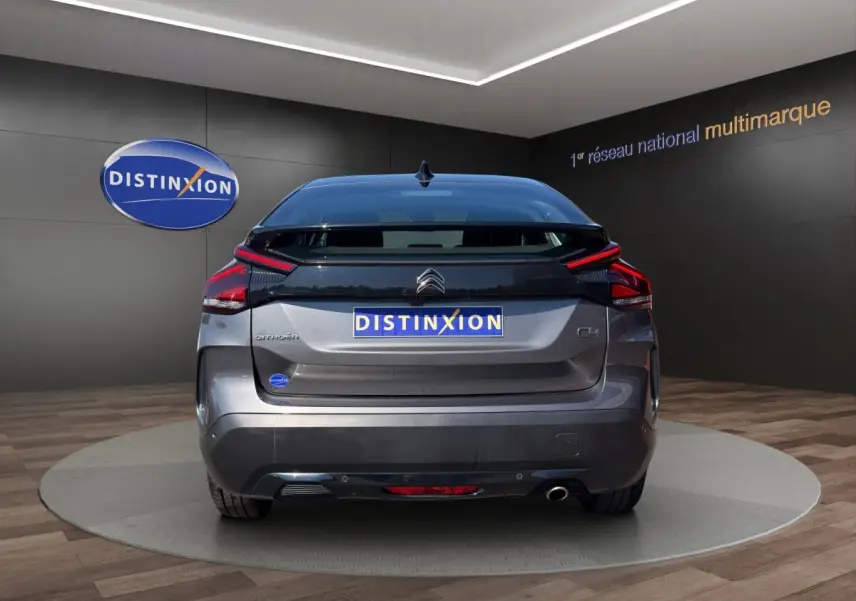 Vue arrière d'une Citroën C4 gris foncé 2023, avec feux LED et logo distinctif sur fond noir.