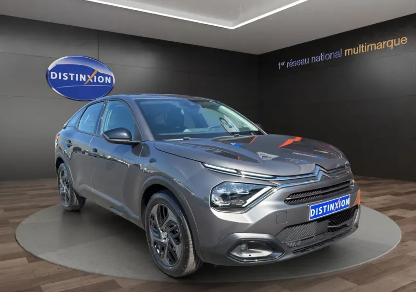 Citroën C4 gris foncé vue 3/4 avant droit, avec phares LED et calandre distinctive en showroom.