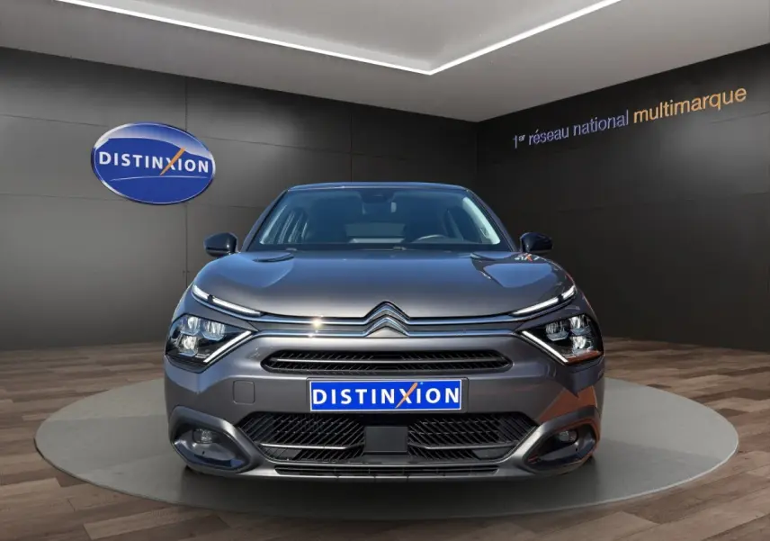 Vue frontale d'une Citroën C4 gris foncé 2023 avec phares LED et calandre distinctive en showroom.