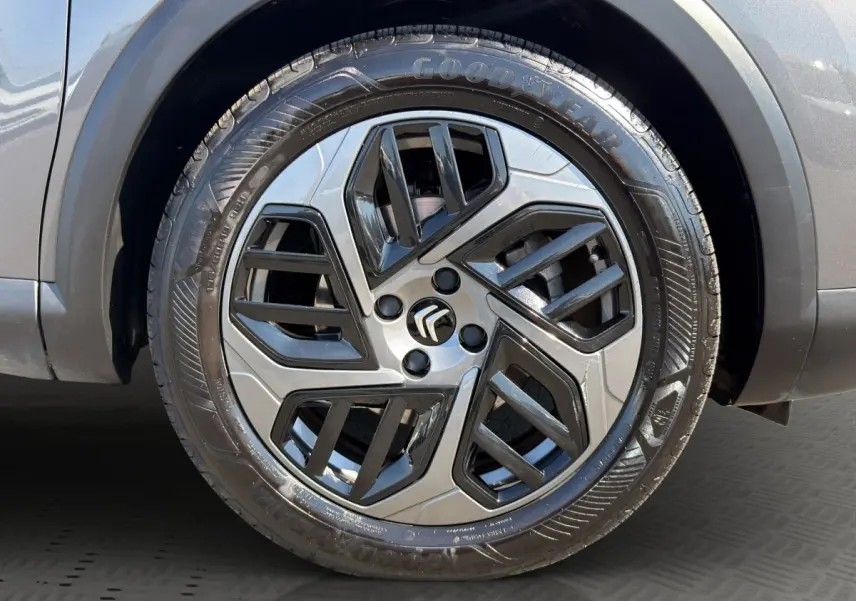 Gros plan sur la roue avant droite d'une Citroën C4 gris foncé, jante alliage au design moderne bicolore.