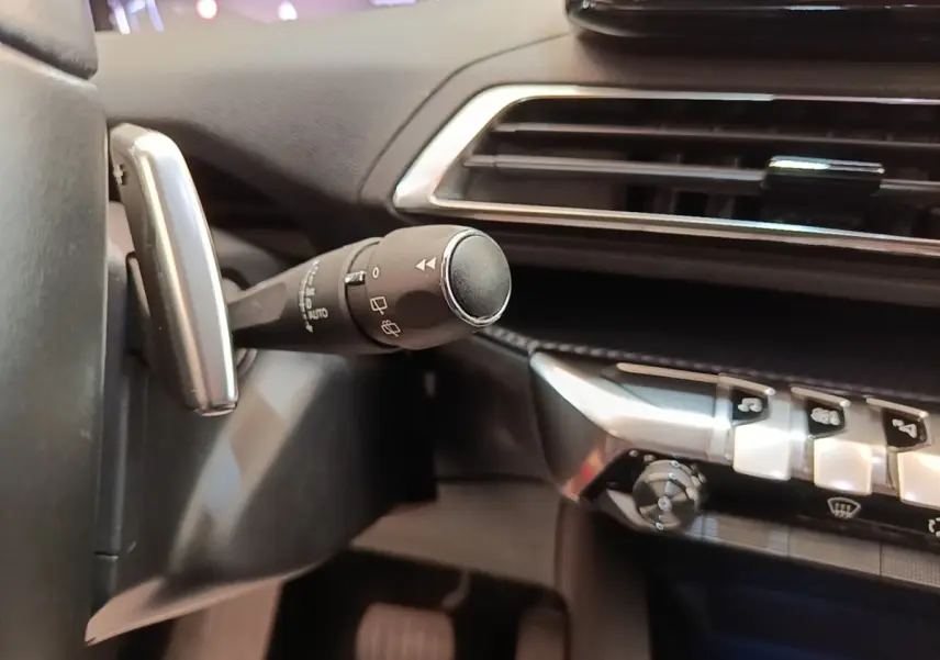Gros plan intérieur sur la commande d’essuie-glace et la console centrale du Peugeot 3008 noir, version Allure 2022.