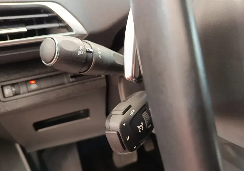 Gros plan sur la commande du régulateur de vitesse derrière le volant cuir noir du Peugeot 3008 PureTech 130 Allure.