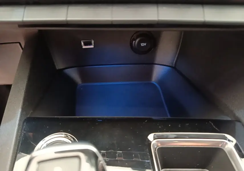 Gros plan sur la console centrale noire du Peugeot 3008 avec prise 12V et port USB visible.