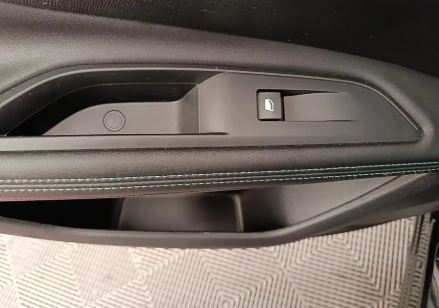 Gros plan sur la poignée intérieure côté droit de la porte d’un Peugeot 3008 noir avec couture bleue décorative.