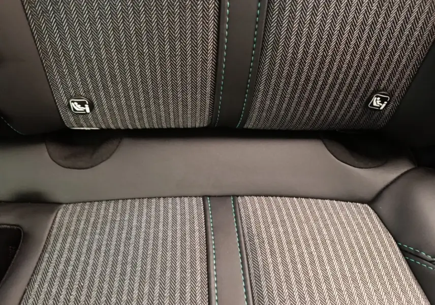 Gros plan sur la banquette arrière du Peugeot 3008 noir, tissu à motif chevrons avec surpiqûres vertes et logos Isofix.