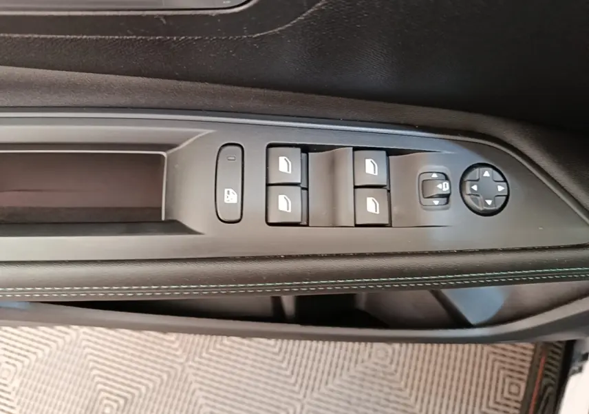 Gros plan sur la commande des vitres électriques côté conducteur du Peugeot 3008 noir, avec surpiqûres blanches sur la garniture.