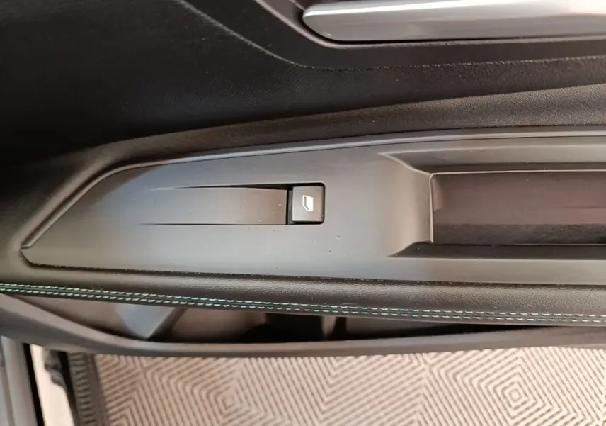 Détail de la commande de lève-vitre sur la porte intérieure côté conducteur d’un Peugeot 3008 noir 2022.