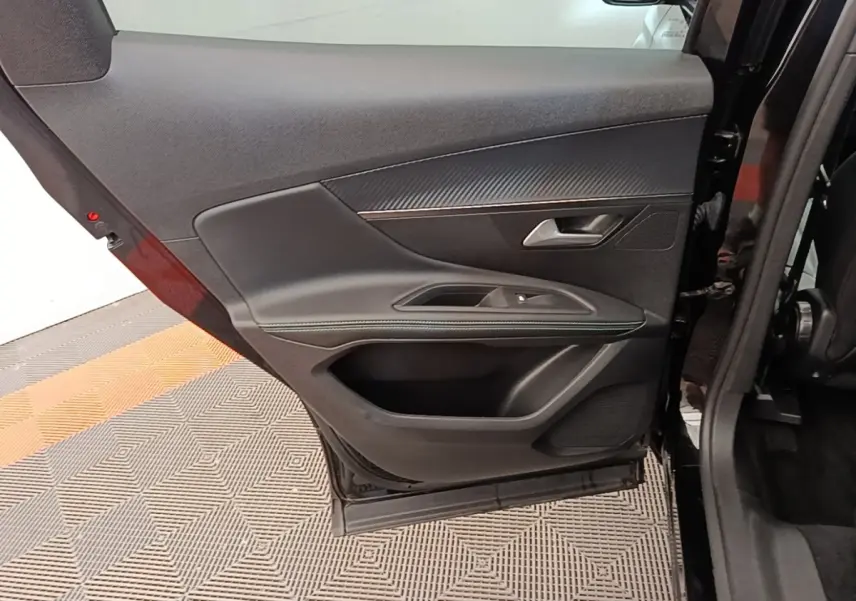 Vue intérieure de la porte arrière droite noire d’un Peugeot 3008, avec garniture tissu et surpiqûres vertes.