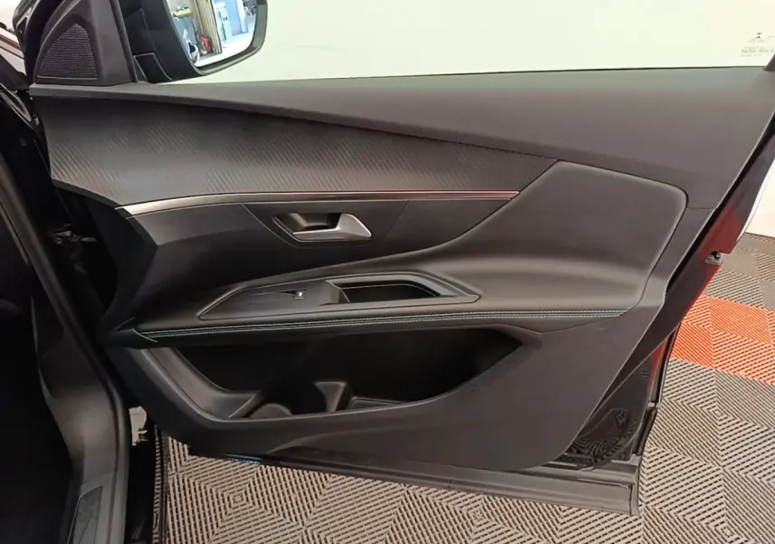 Vue intérieure de la porte avant gauche noire du Peugeot 3008 2022 avec garniture texturée et surpiqûres contrastées.
