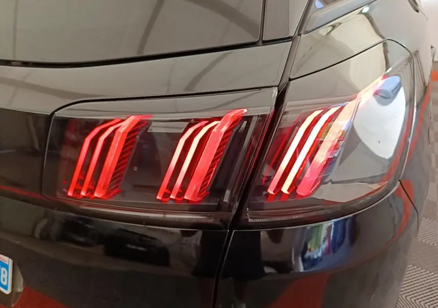 Gros plan sur les feux arrière rouges du côté gauche d’un Peugeot 3008 noir, finition Allure 2022.
