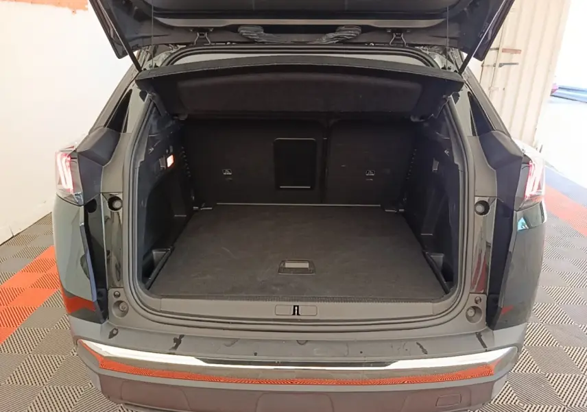 Coffre ouvert vu de l'arrière d'un Peugeot 3008 noir, montrant un espace de chargement spacieux et propre.
