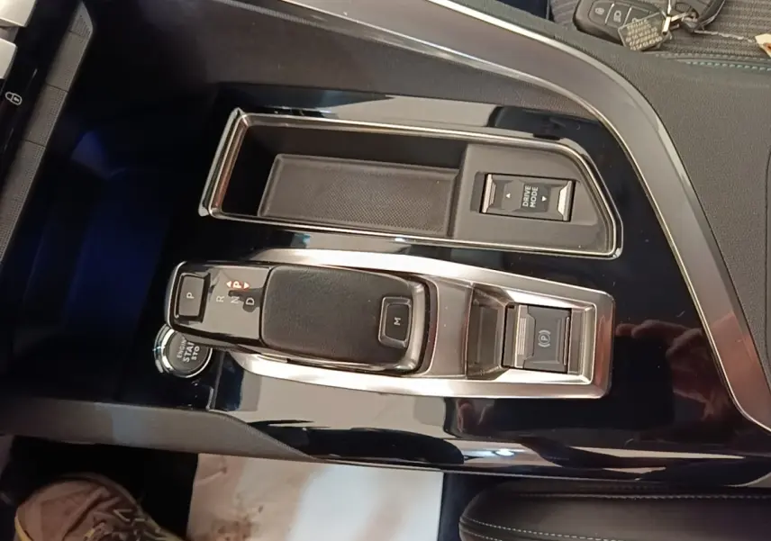 Vue rapprochée de la console centrale noire brillante du Peugeot 3008 avec levier de vitesse automatique et boutons multifonctions.