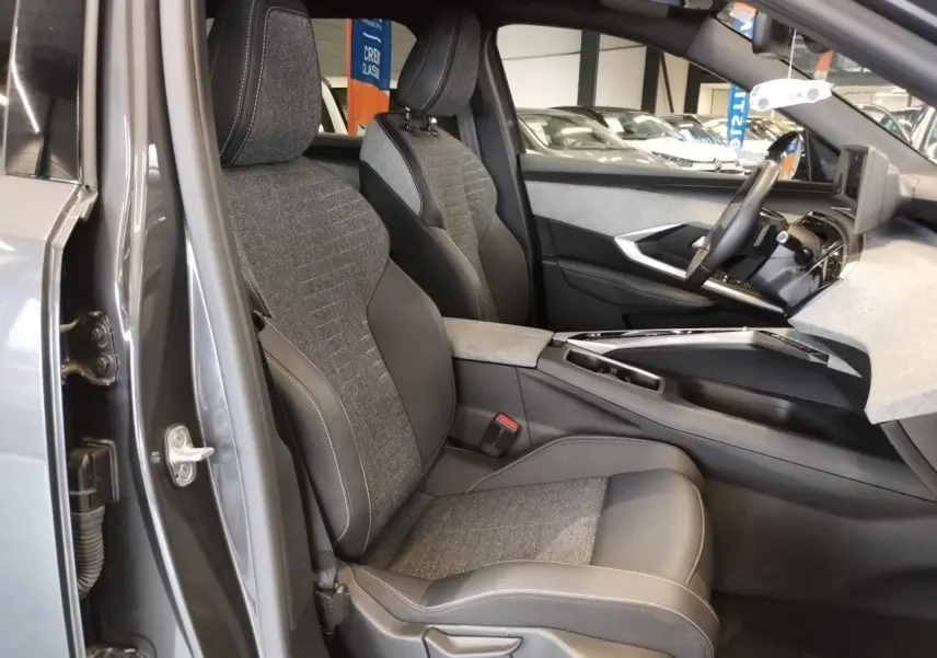 Intérieur avant droit du Peugeot 5008 gris titanium 2025, sièges tissu et cuir avec surpiqûres contrastées.