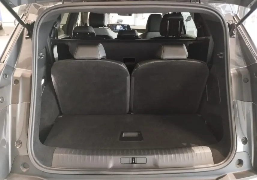 Coffre ouvert d’un Peugeot 5008 gris titanium, vue arrière montrant la banquette rabattue et l’habitacle intérieur.