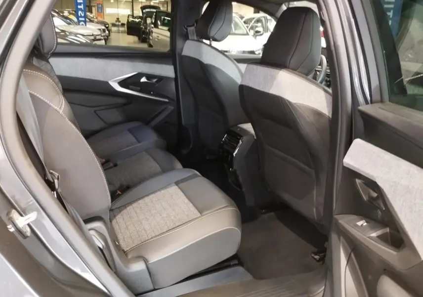 Vue intérieure côté gauche sur la banquette arrière tissu gris et noir du Peugeot 5008 1.2i Hybrid 2025 gris titanium.