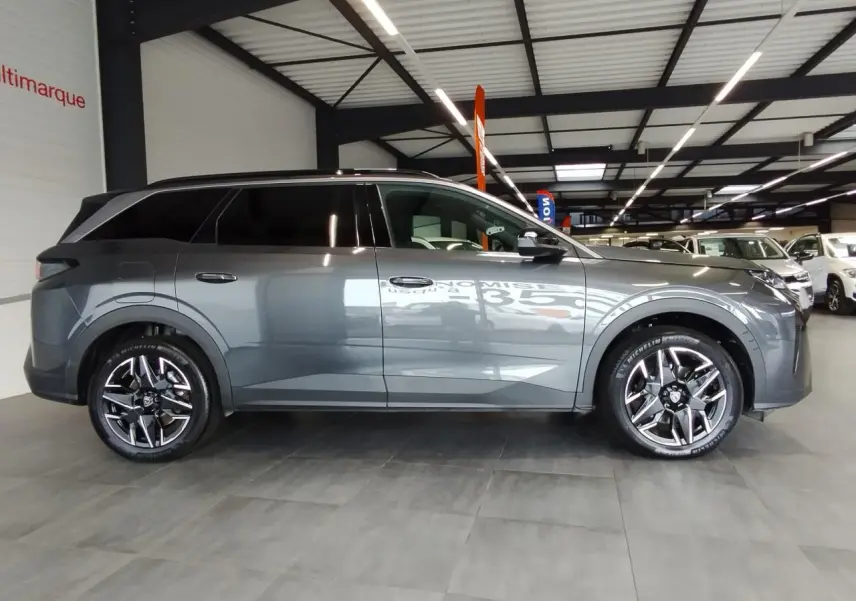 Peugeot 5008 gris titanium vue de profil côté gauche avec jantes alliage 19'' diamantées en intérieur showroom.