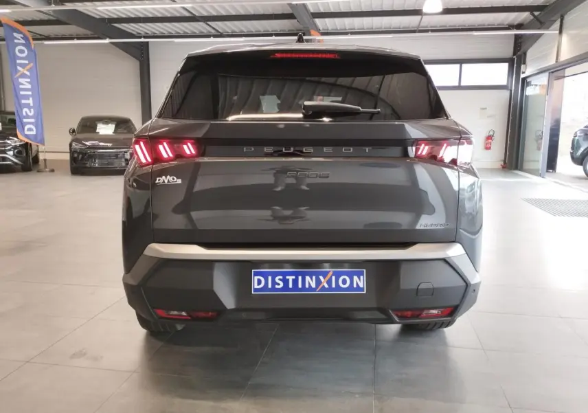 Vue arrière d’un Peugeot 5008 gris titanium avec feux arrière LED allumés dans un showroom.
