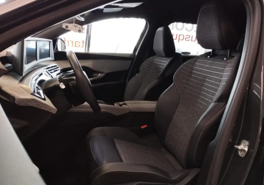 Vue intérieure côté conducteur du Peugeot 5008 gris titanium 2025, sièges tissu et cuir avec planche de bord moderne.