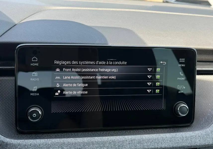 Écran tactile central du Skoda Kamiq 2025 affichant les réglages des aides à la conduite, intérieur gris et noir.