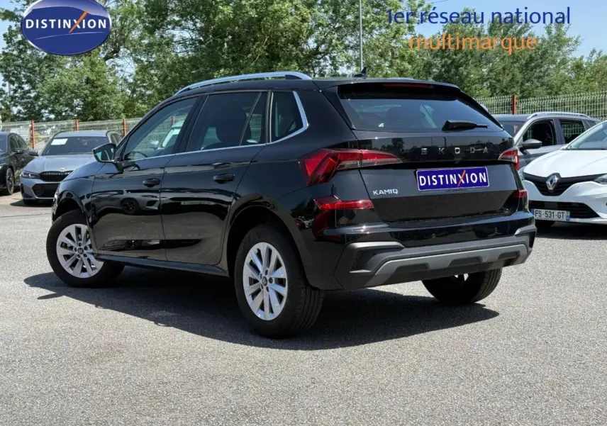 Vue 3/4 arrière droite d’un Skoda Kamiq 2025 noir Magic nacré avec jantes argentées sur parking extérieur.
