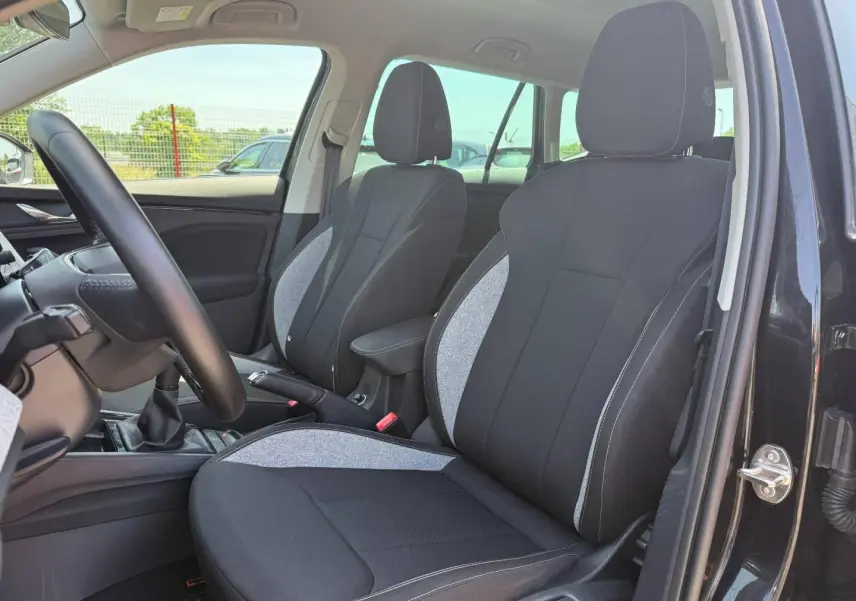 Vue intérieure côté conducteur du Skoda Kamiq 2025 noir Magic nacré, sièges tissu bicolore avec surpiqûres blanches.