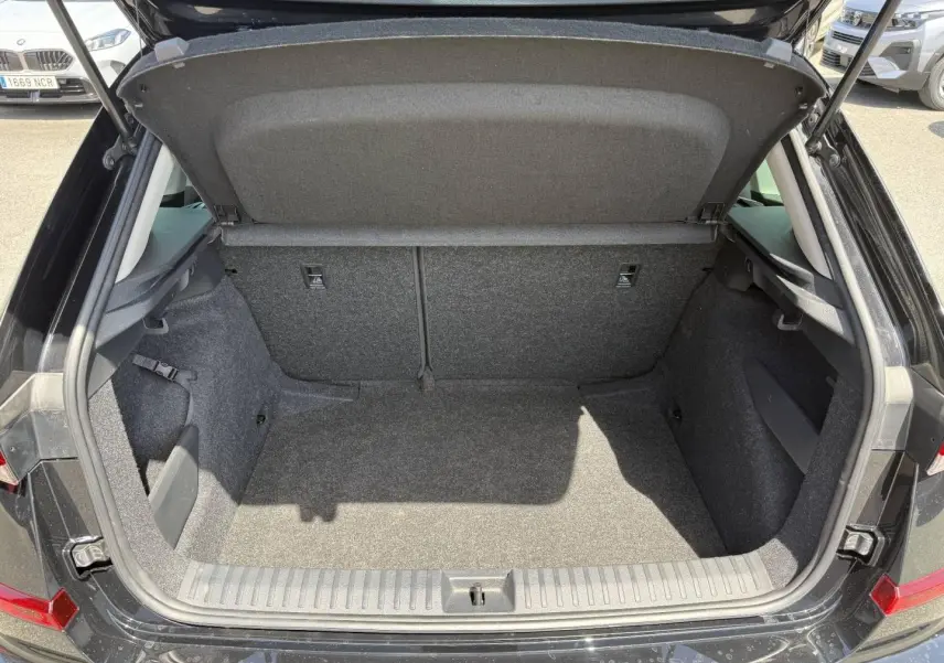Coffre ouvert vu de l'arrière d'un Skoda Kamiq 2025 noir Magic nacré, montrant un espace de chargement vide et propre.
