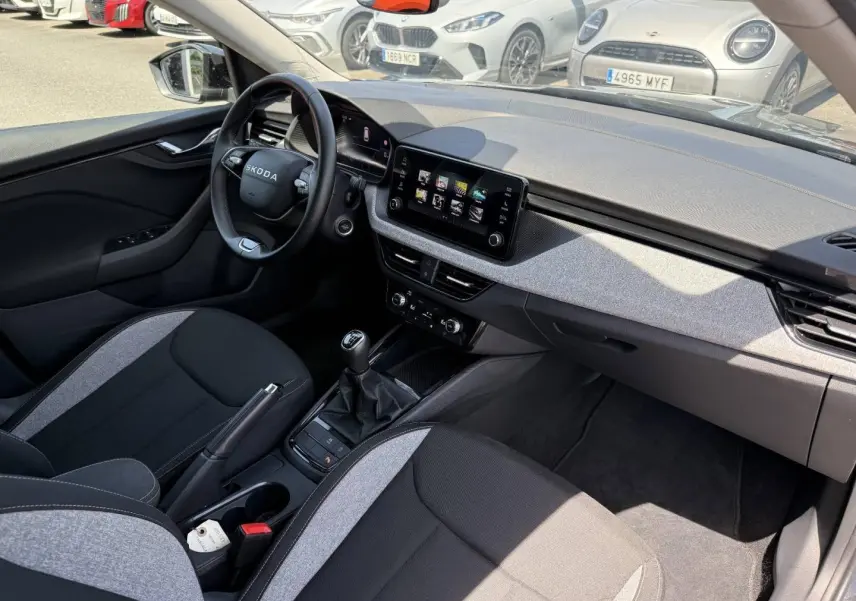 Vue intérieure côté conducteur du Skoda Kamiq 2025, avec tableau de bord moderne et sellerie bicolore noire et grise.