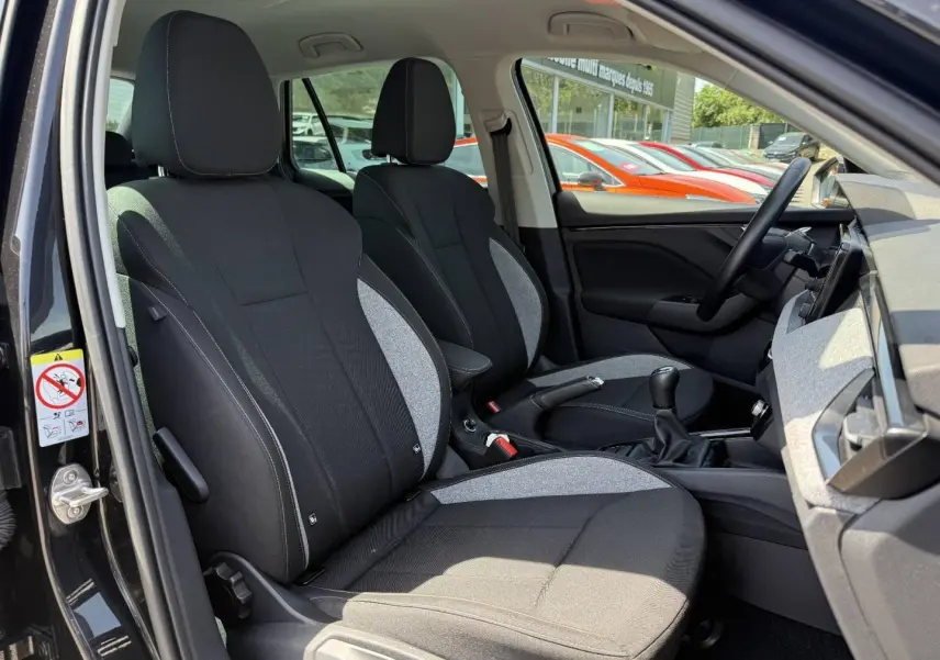 Vue intérieure côté conducteur du Skoda Kamiq 2025 noir Magic nacré, montrant les sièges tissu bicolore et la boîte manuelle.