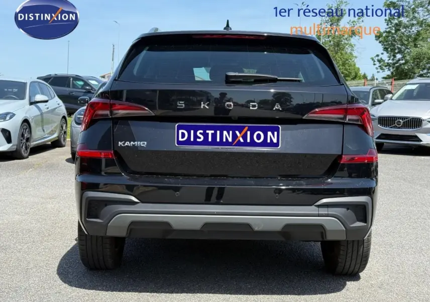 Vue arrière d'un Skoda Kamiq noir Magic nacré 2025 avec logo et plaque Distinxion visible en extérieur.