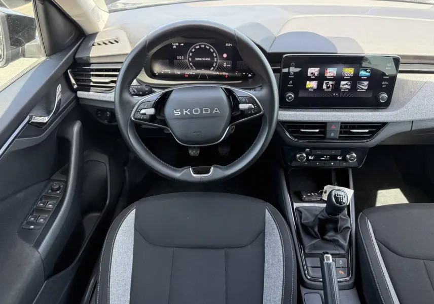 Vue intérieure frontale du Skoda Kamiq 2025, volant multifonction, écran tactile et levier de vitesses manuel visibles.