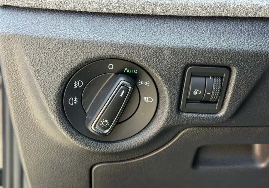 Gros plan sur la commande d’éclairage intérieur du Skoda Kamiq 2025 en Noir Magic nacré, avec réglage automatique des phares.