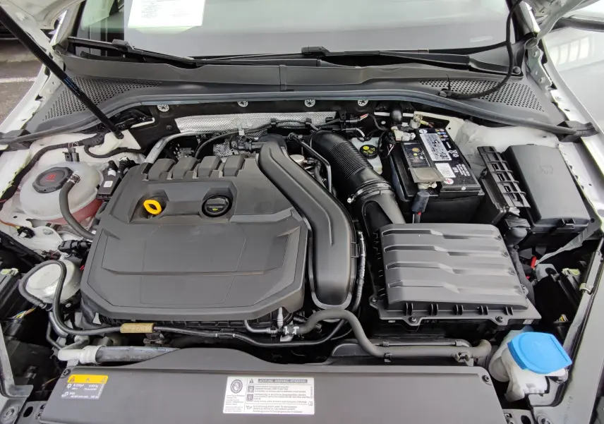 Vue plongeante sur le moteur essence d'une Volkswagen Golf blanche 1.5 TSI EVO 150CV avec capot ouvert.
