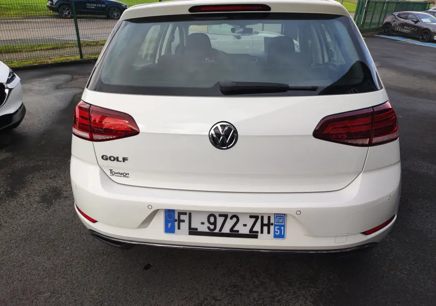 Vue arrière d'une Volkswagen Golf blanche de 2019 avec feux rouges et logo VW bien visibles.