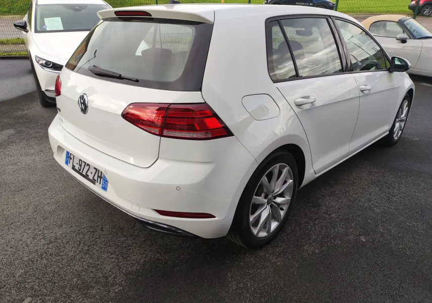 Vue 3/4 arrière droite d'une Volkswagen Golf blanche 1.5 TSI EVO 2019 avec jantes alliage et feux arrière LED.