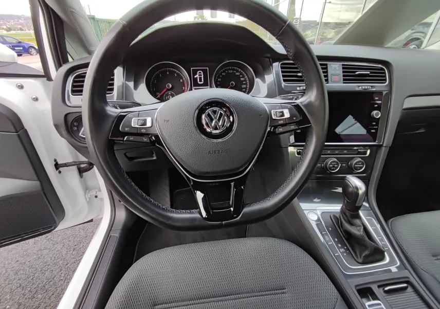 Vue intérieure centrée sur le volant et la console d’une Volkswagen Golf blanche 1.5 TSI EVO 2019 avec boîte auto.