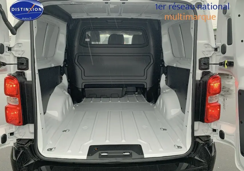 Vue arrière du Peugeot Expert Long blanc Kaolin avec portes ouvertes montrant l'espace de chargement vide et la cloison de séparation noire.