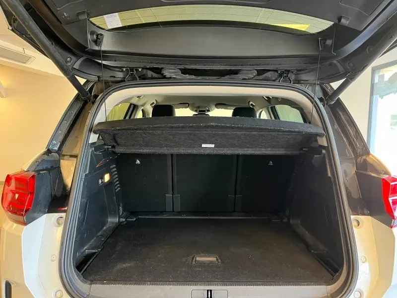 Coffre ouvert vu de l'arrière d'un Citroën C5 Aircross blanc nacré, montrant l'espace de chargement et la tablette cache-bagages.