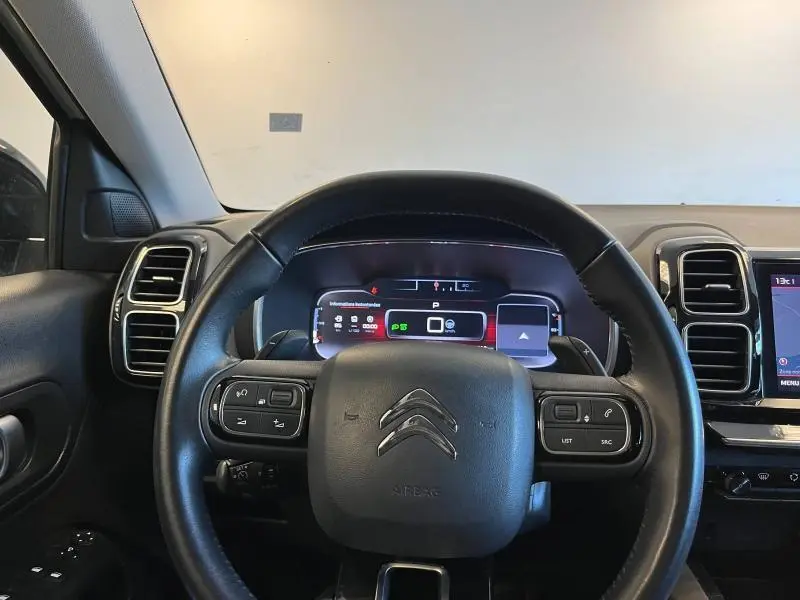 Vue intérieure centrée sur le volant cuir noir de la Citroën C5 Aircross avec tableau de bord numérique et commandes intégrées.