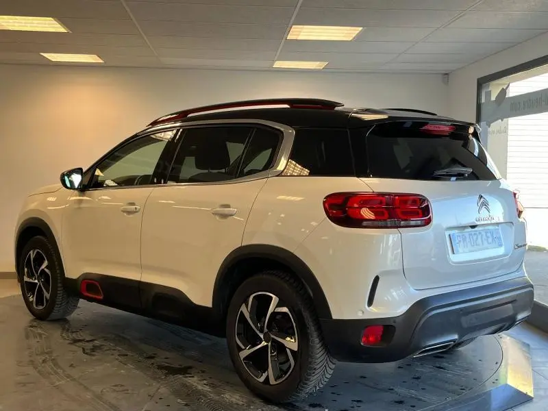 Vue 3/4 arrière droite d'un Citroën C5 Aircross blanc nacré avec toit noir et jantes alu distinctives.
