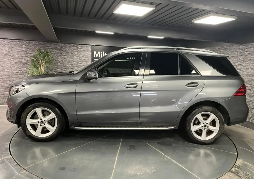 Profil côté gauche d'un Mercedes GLE 400 gris métallisé avec jantes alliage 19 pouces et vitres teintées.