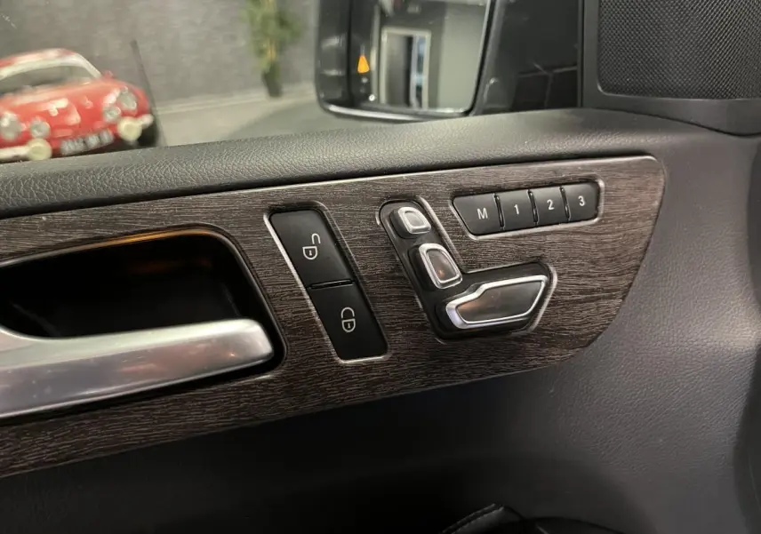 Détail des commandes de réglage de siège sur la porte côté gauche d'une Mercedes GLE 400 gris, finition cuir.