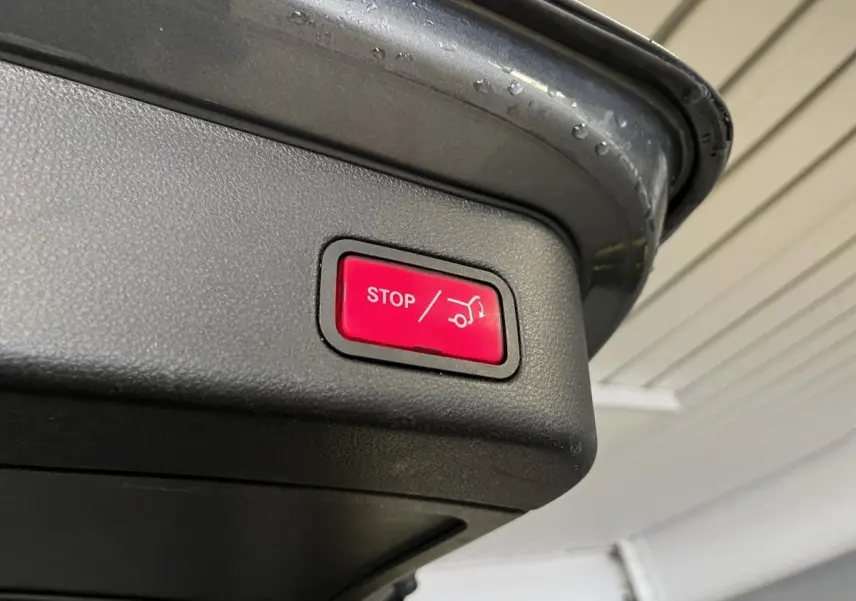 Bouton rouge stop pour fermeture électrique du hayon sur un Mercedes GLE gris, vue en gros plan du coffre ouvert.