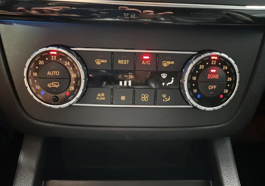Panneau de commande de climatisation automatique bi-zone du Mercedes GLE 400 gris, avec réglages et voyants lumineux rouges.