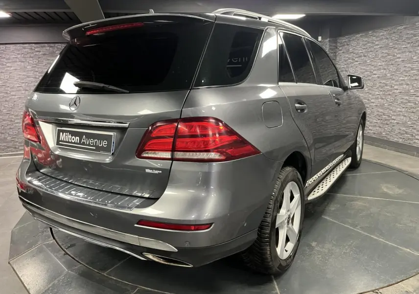 Vue 3/4 arrière droite d'un Mercedes GLE 400 gris métallisé avec jantes alliage et vitres teintées foncées.