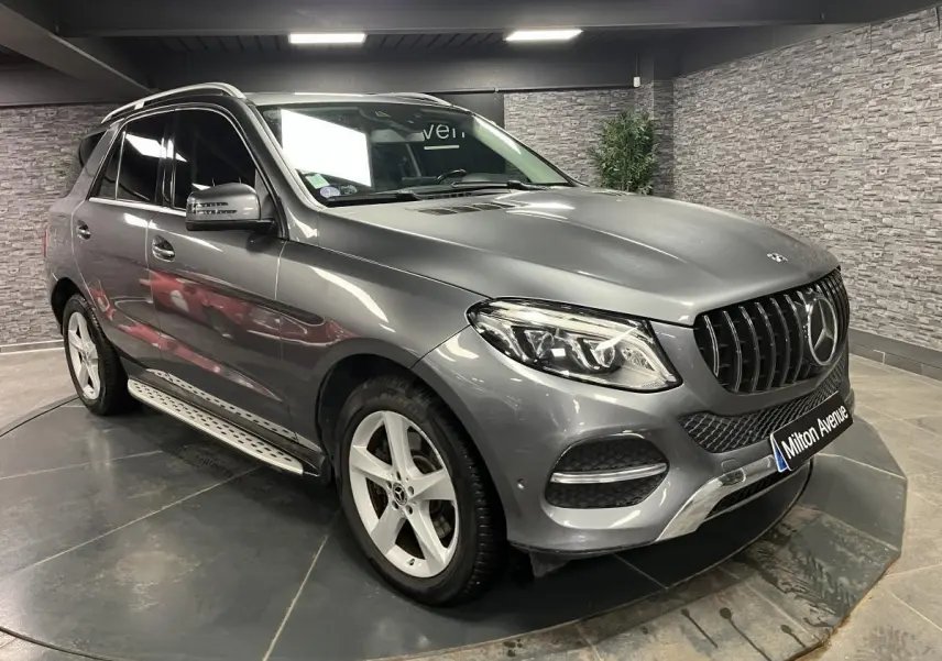Vue 3/4 avant droite d'un Mercedes GLE 400 gris métallisé avec jantes alliage et barres de toit chromées.