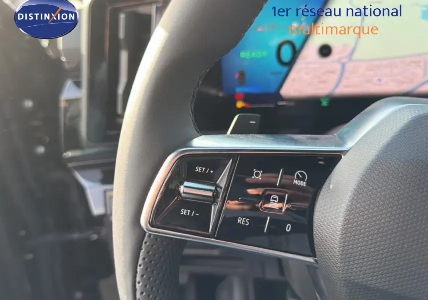 Gros plan sur les commandes du volant d'un Renault Espace noir étoile métal, avec écran numérique en arrière-plan.