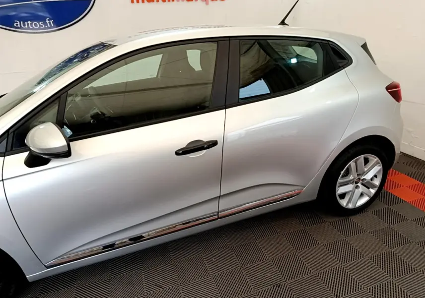 Profil côté gauche d'une Renault Clio Business TCe 100 gris clair, soulignant la ligne de caisse chromée et les jantes alliage.