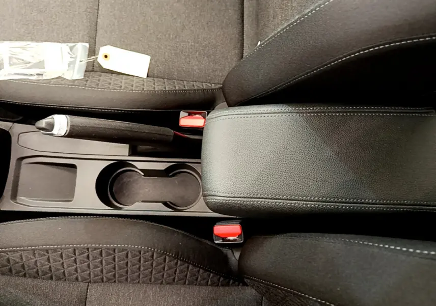 Vue plongeante sur la console centrale noire de la Renault Clio Business TCe 100 avec frein à main manuel et accoudoir cuir.